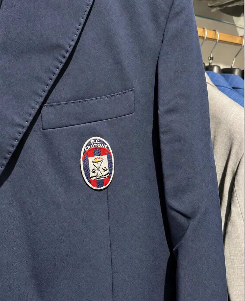 Giacca blu con stemma FC Crotone sul taschino.