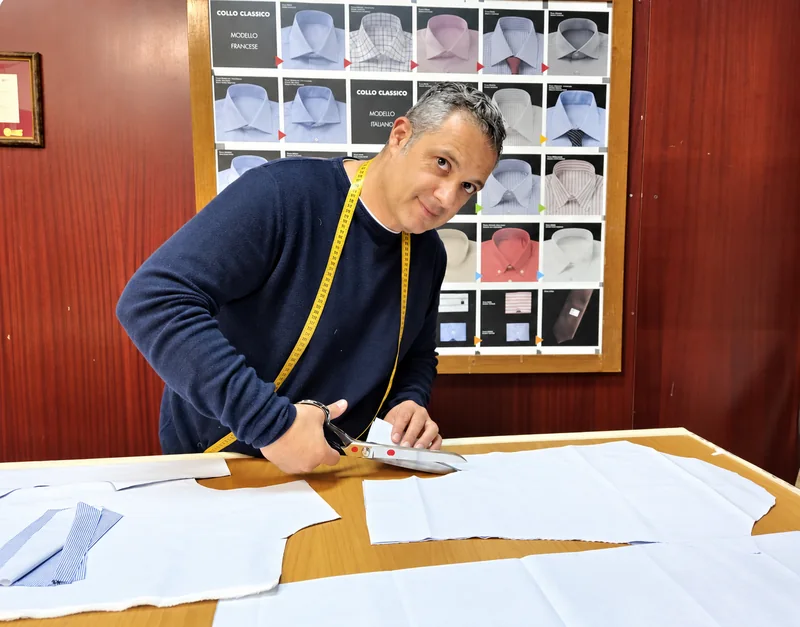 Antonio Gigliotti al banco mentre lavora una camicia nel suo laboratorio.