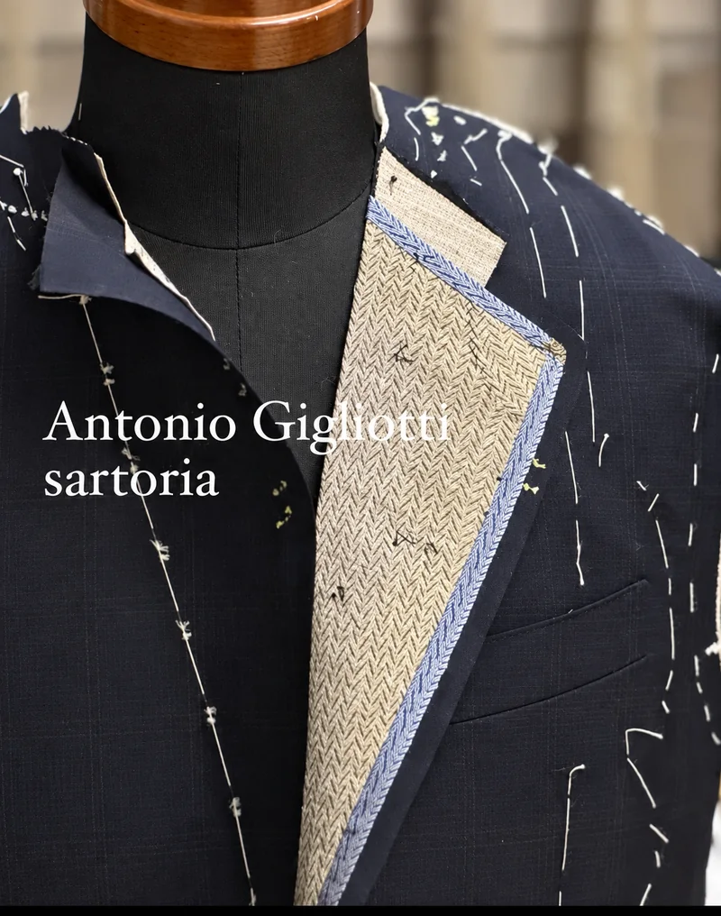Lavorazione sartoriale su manichino, con imbastiture e dettagli del modello.
