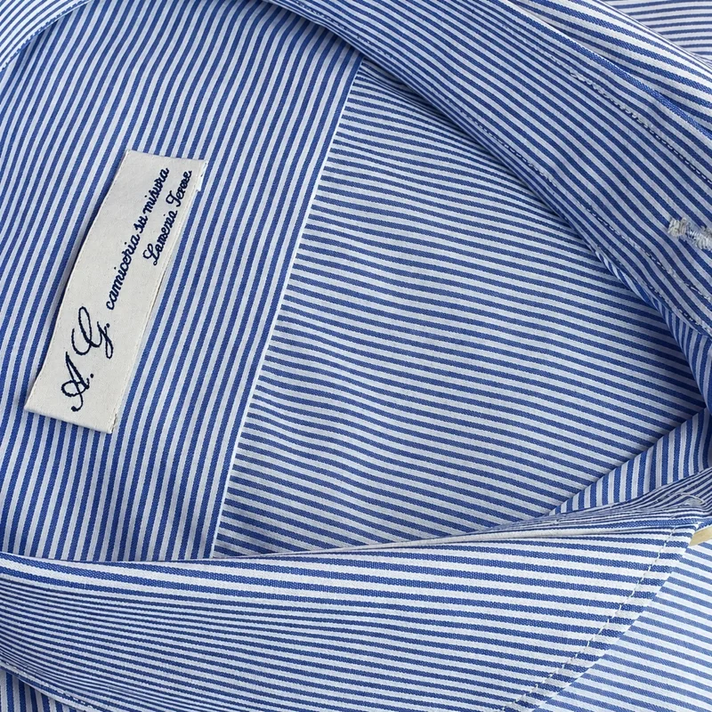 Dettaglio del collo di una camicia a righe blu e bianche con etichetta della camiceria Antonio Gigliotti.